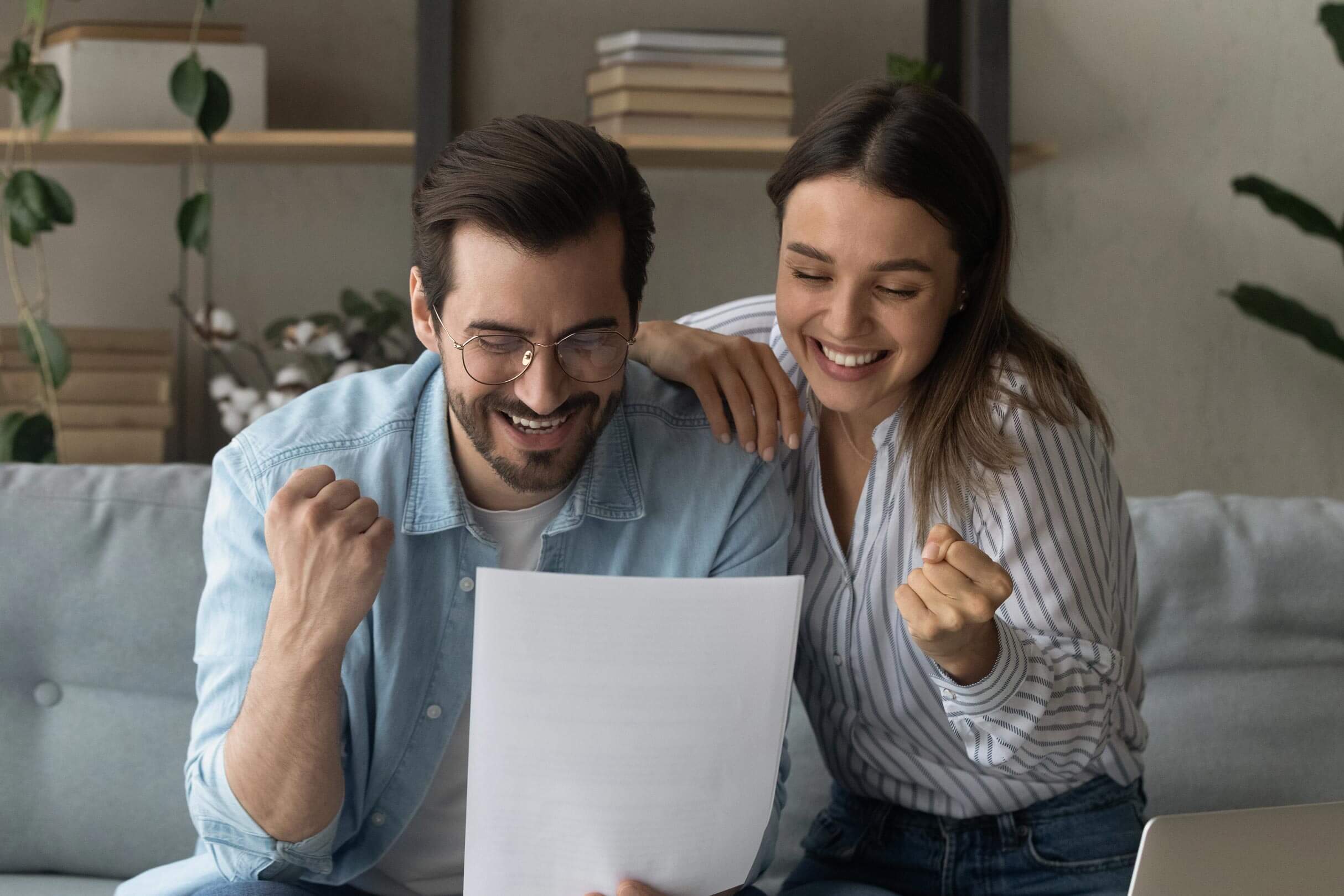 Ein lachendes Pärchen mit der Finanzplanung in der Hand