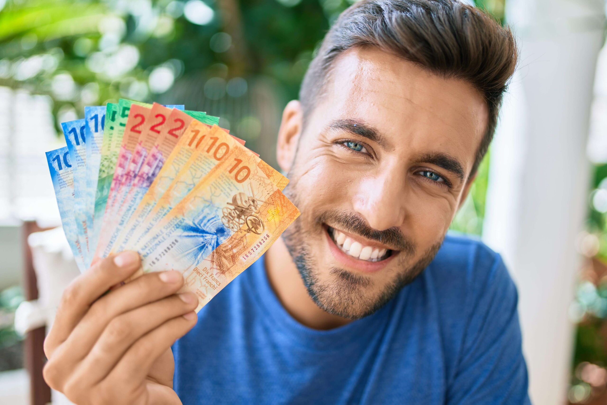 Ein lachender Mann hält Geldnoten in seiner Hand