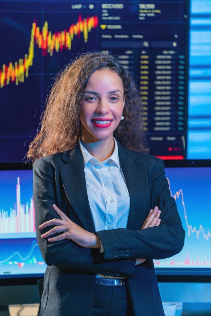 Bild einer Frau vor einem Bildschirm der Börsenkurze zeigt